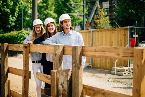 drei Azubis mit Helm auf Baustelle 