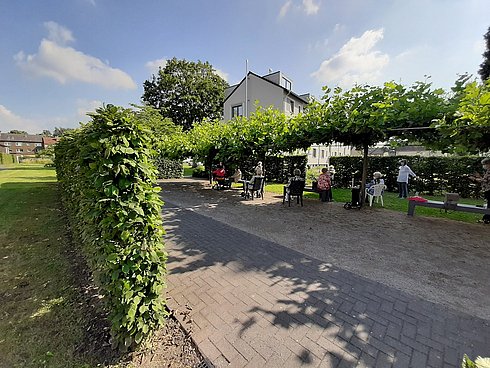 Gruppe von Menschen sitzt auf Gartenstühlen im Grünen
