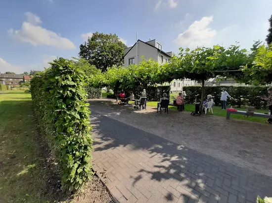 Gruppe von Menschen sitzt auf Gartenstühlen im Grünen