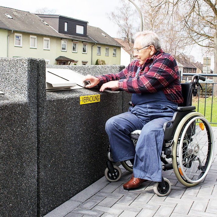 Mann im Rollstuhl an barierrefreien Mülleimern