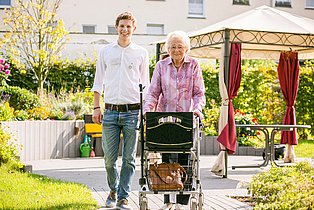 alte Dame und junger Mitarbeiter im barrierefreien WSG Wohnpark alte Dame mit Rollator und ein Mitarbeiter in Wohnpark