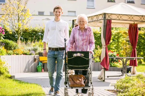 alte Dame mit Rollator und ein Mitarbeiter in Wohnpark