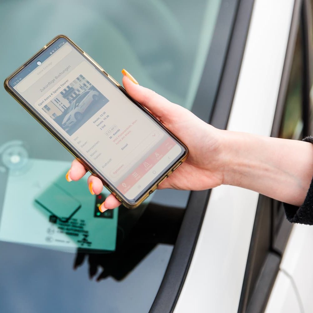 Hand hält Handy mit offener Car-sharing Website 